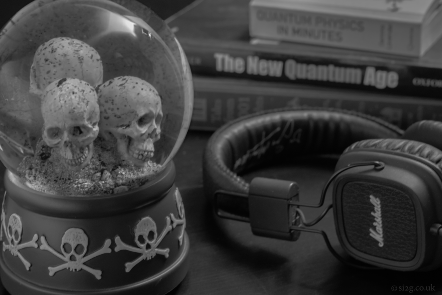 Quantum Physics - A skull-themed snow globe sits next to other objects on the bedside table.